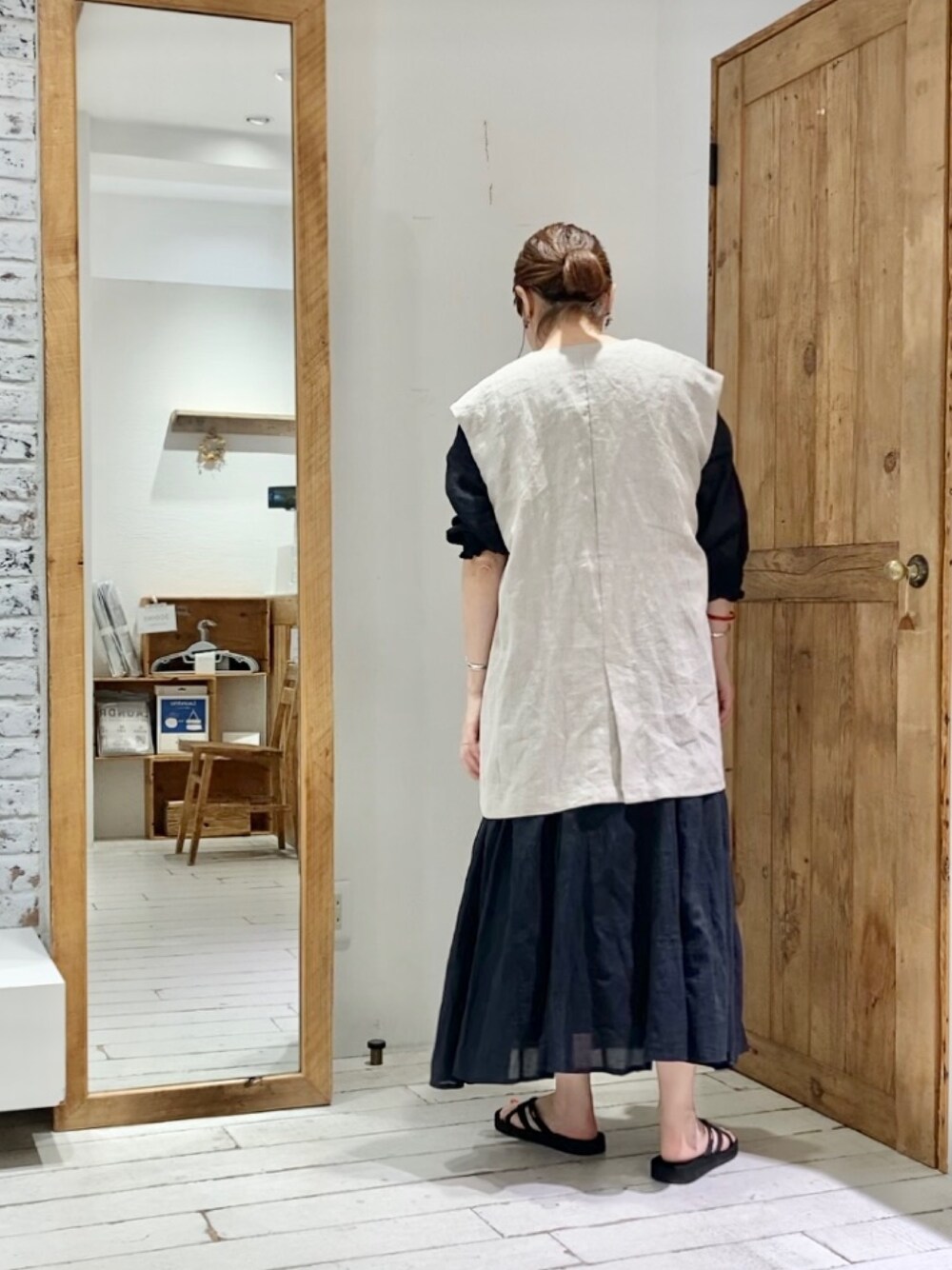 ベージュ系のベスト、ブラック系のワンピースを着用したレディースの夏コーディネートの3枚目の写真