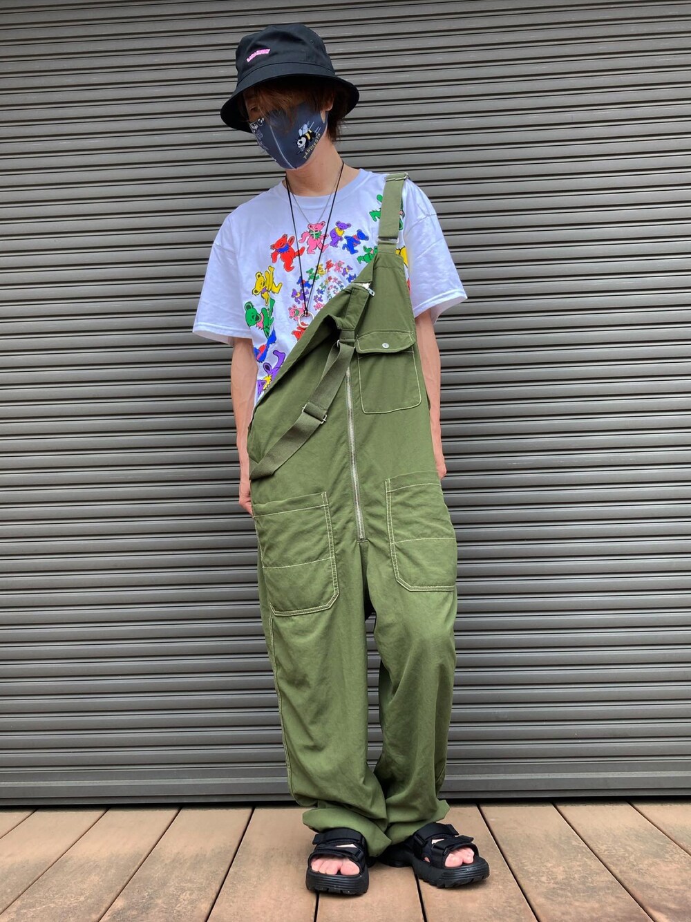 ホワイト系のTシャツ/カットソー、グリーン系のサロペット/オーバーオール、ブラック系のサンダルを着用したメンズの夏コーディネートの1枚目の写真
