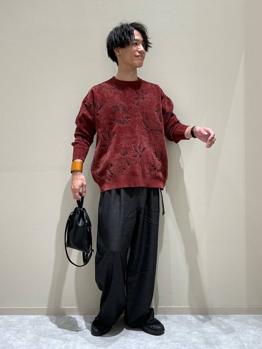 ブラック系のショルダーバッグ、レッド系のニット/セーター、グレー系のスラックスを着用したメンズの秋コーディネートの1枚目の写真