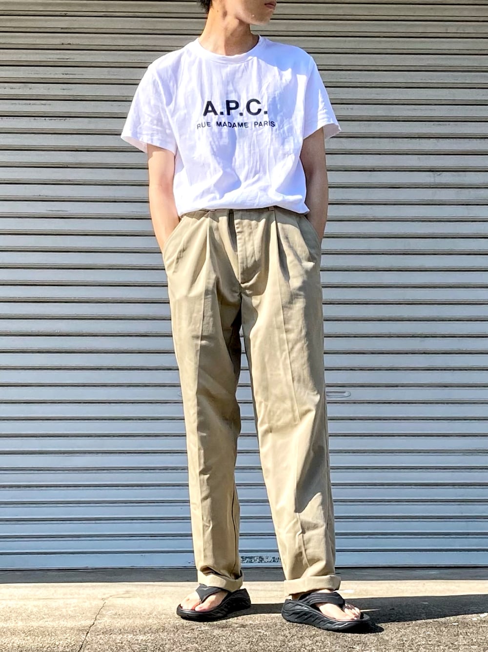 ホワイト系のTシャツ/カットソー、ベージュ系のチノパンツ、ブラック系のサンダルを着用したメンズの夏コーディネートの1枚目の写真