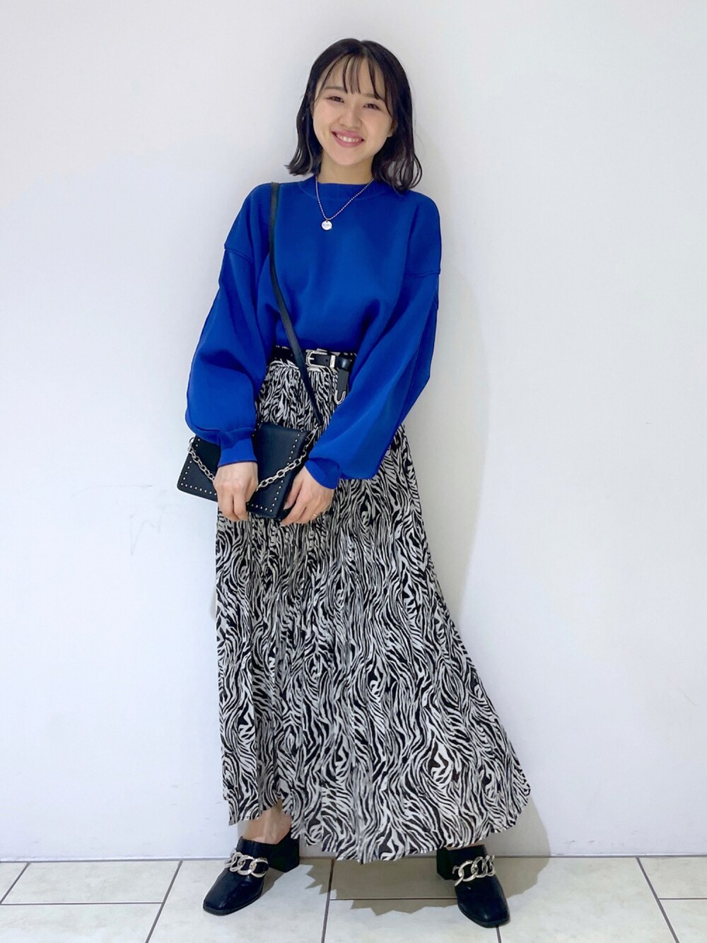 ブルー系のニット/セーター、その他のスカート、ブラック系のサンダルを着用したレディースの秋コーディネートの1枚目の写真