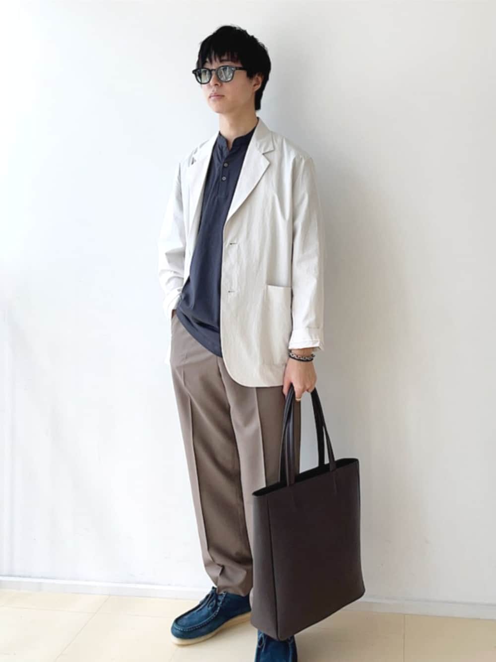 ブラウン系のトートバッグ、ブルー系のブーツ、ブラウン系のスラックスを着用したメンズの夏コーディネートの1枚目の写真