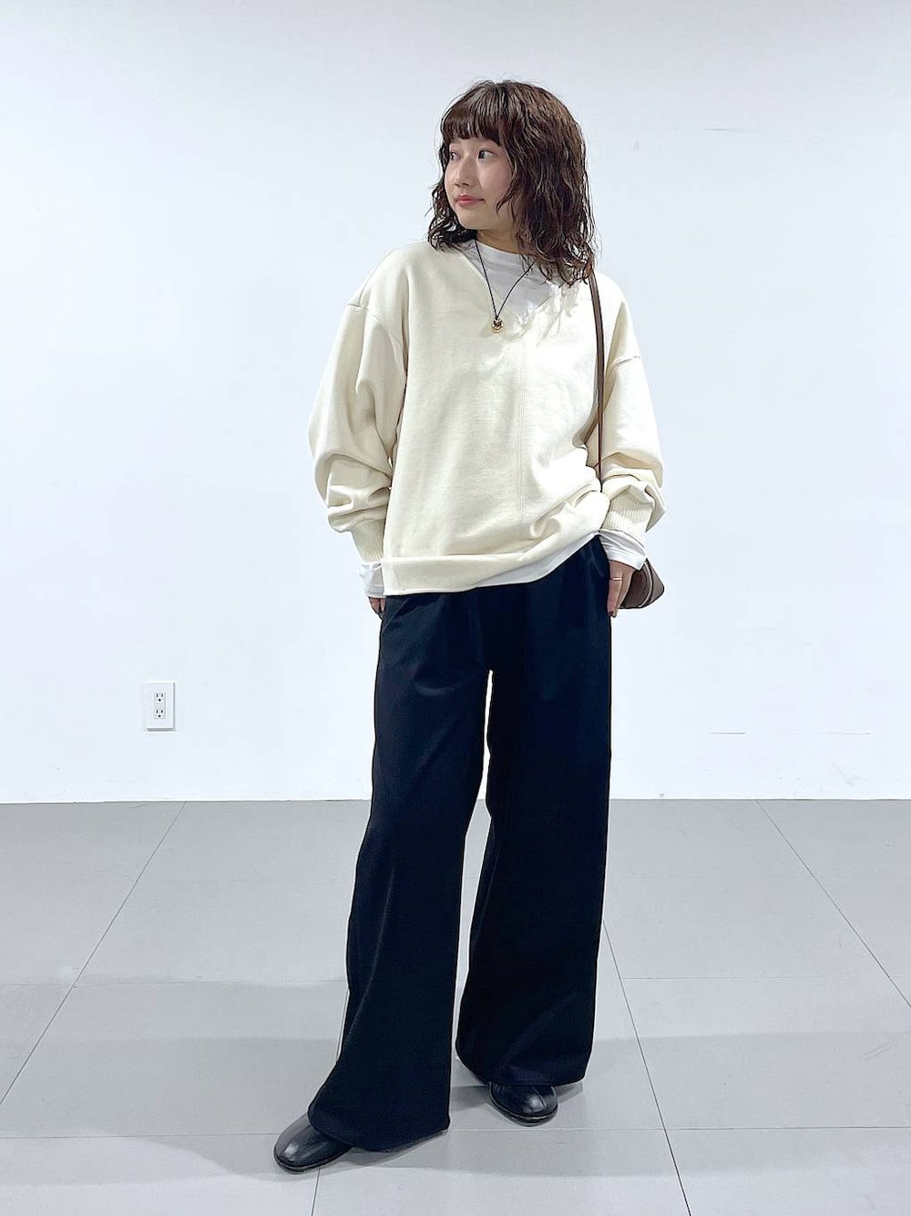 ブラウン系のショルダーバッグ、ブラック系のブーツ、ホワイト系のTシャツ/カットソーを着用したレディースの秋コーディネートの1枚目の写真