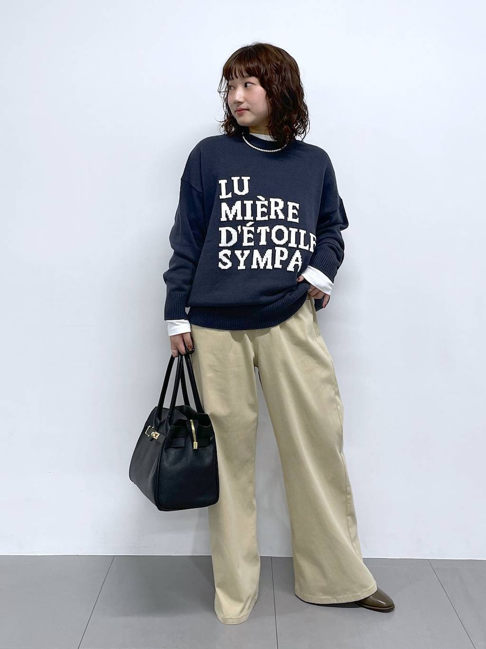 グレー系のニット/セーター、ベージュ系のデニムパンツを着用したレディースの冬コーディネートの1枚目の写真