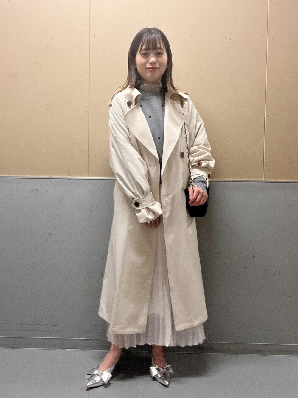 グレー系のニット/セーター、ホワイト系のトレンチコート、シルバー系のパンプスを着用したレディースの春コーディネートの1枚目の写真