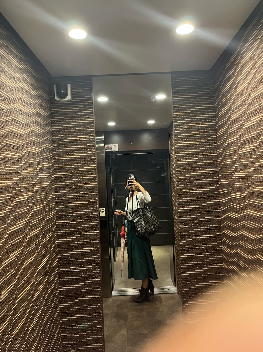 ブラック系のトートバッグ、グリーン系のスカート、ホワイト系のTシャツ/カットソーを着用したレディースの秋コーディネートの1枚目の写真