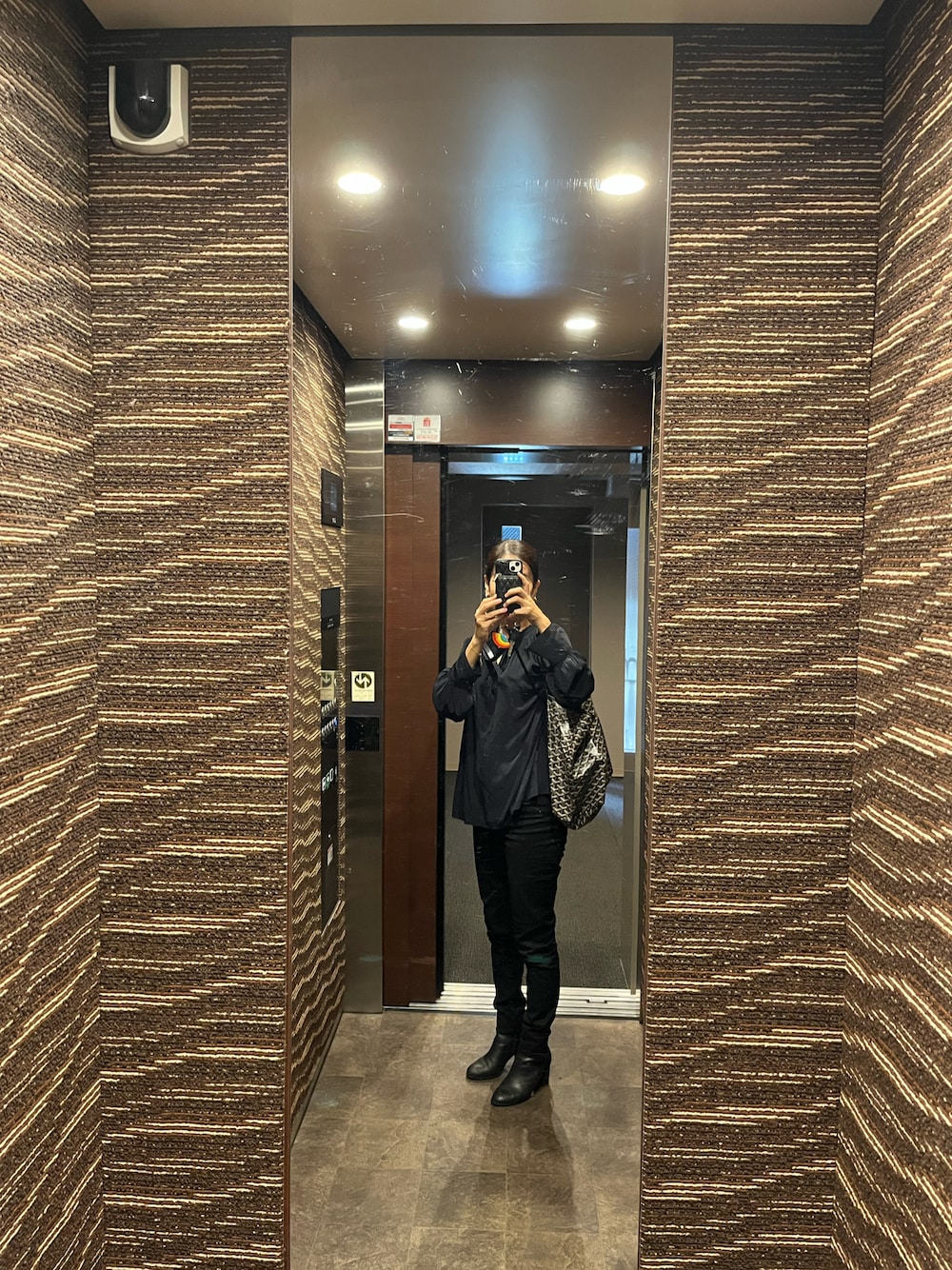 ブラック系のデニムパンツ、ブルー系のシャツ/ブラウス、ブラック系のブーツを着用したレディースの秋コーディネートの1枚目の写真