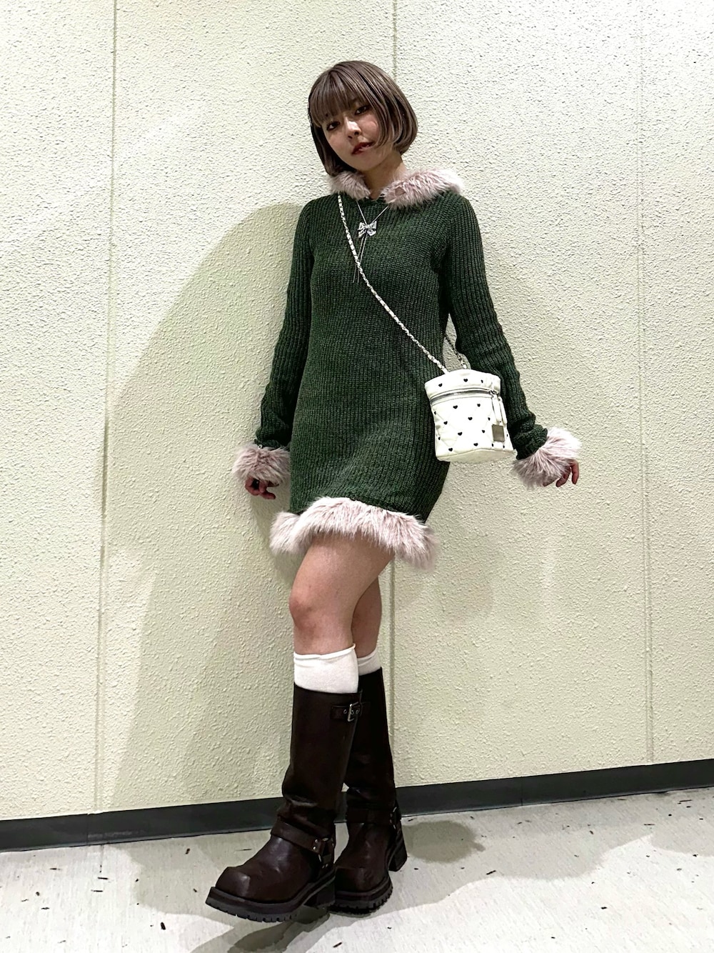 グリーン系のワンピース、ホワイト系のショルダーバッグ、ブラウン系のブーツを着用したレディースの秋コーディネートの1枚目の写真