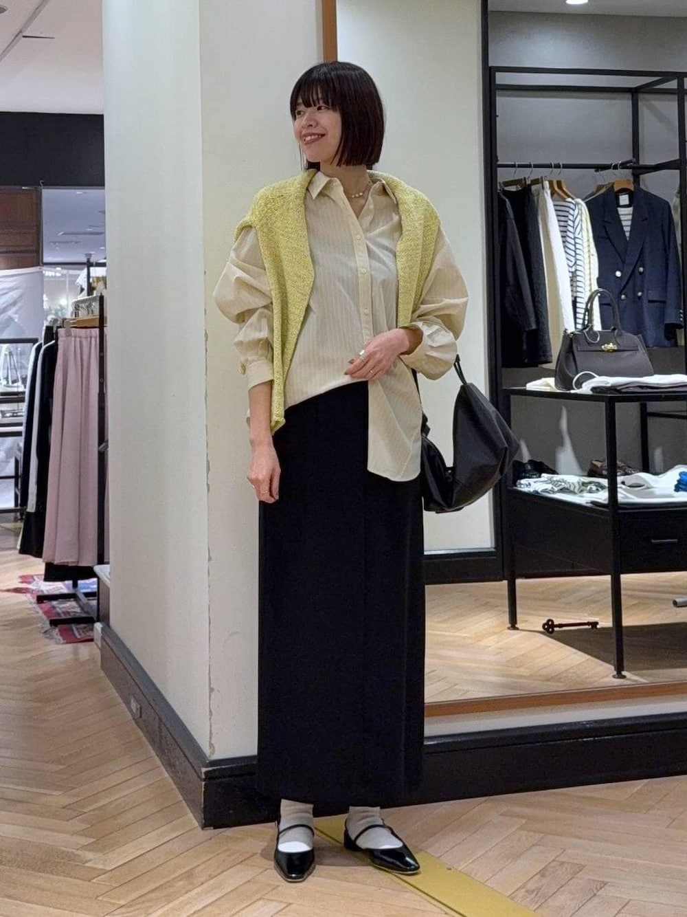 ブラック系のショルダーバッグ、イエロー系のニット/セーター、イエロー系のシャツ/ブラウスを着用したレディースの冬コーディネートの1枚目の写真