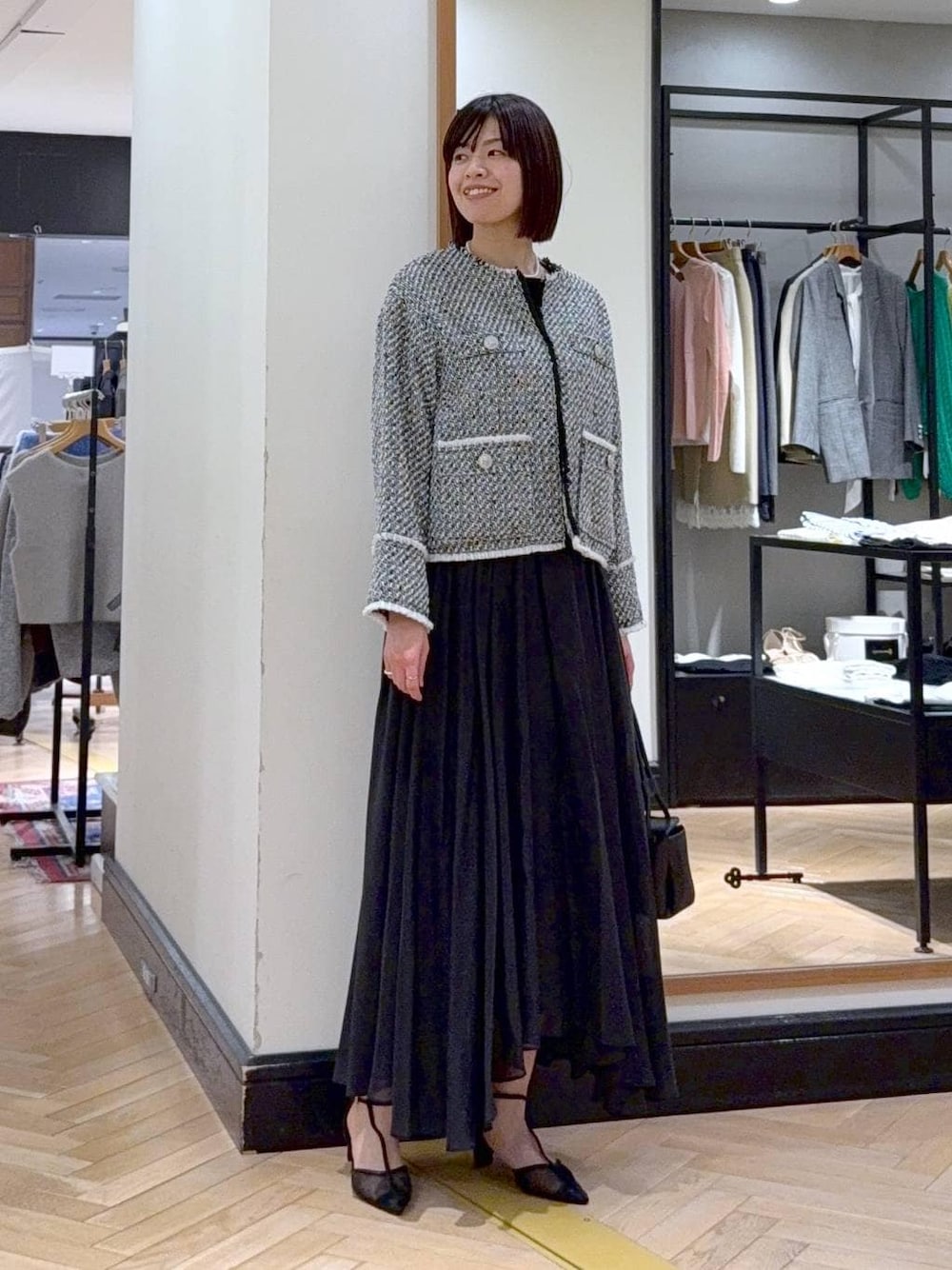 ブラック系のスカート、ブラック系のノーカラージャケット、ブラック系のパンプスを着用したレディースの冬コーディネートの1枚目の写真