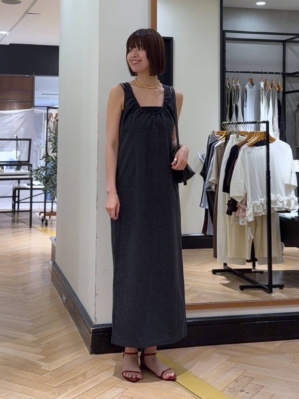 ブラック系のショルダーバッグ、レッド系のサンダル、グレー系のワンピースを着用したレディースの夏コーディネートの1枚目の写真