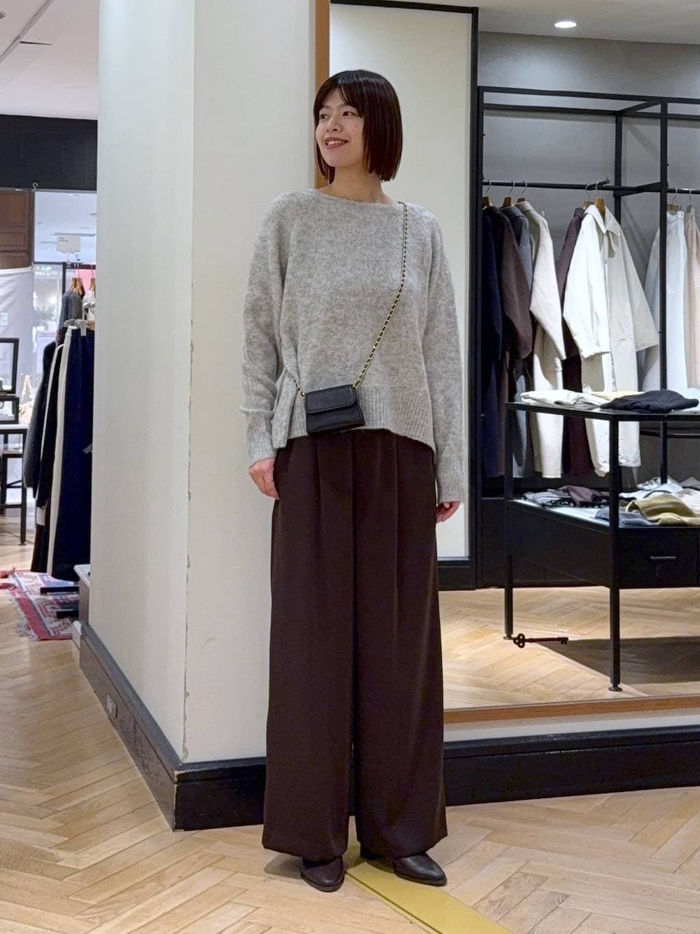 ブラウン系のブーツ、グレー系のニット/セーター、ブラウン系のスラックスを着用したレディースの秋コーディネートの1枚目の写真