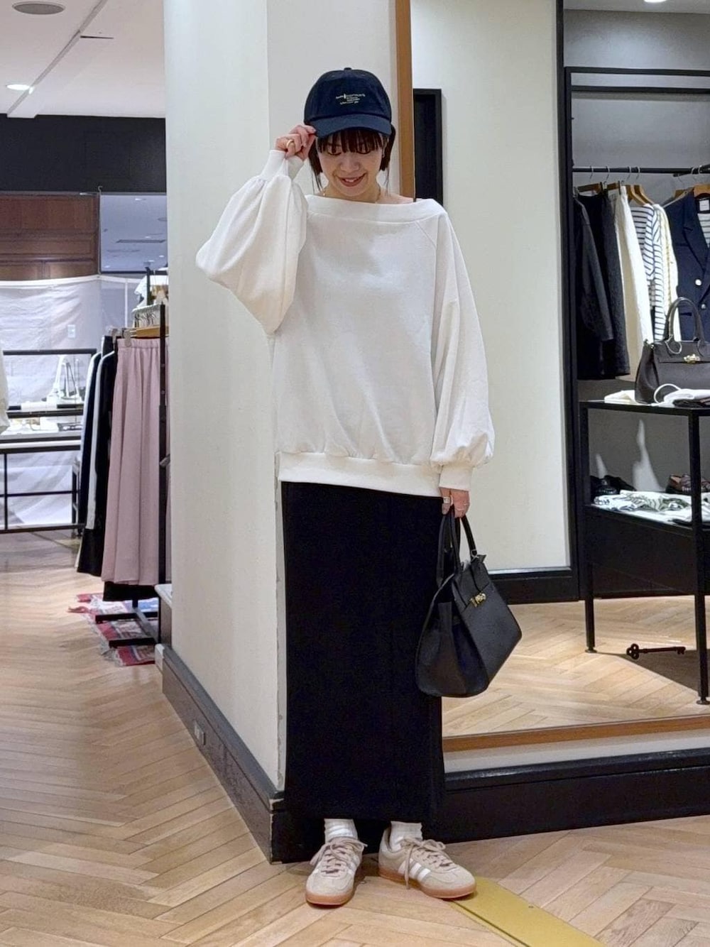 ベージュ系のスニーカー、ブラック系のショルダーバッグ、ホワイト系のスウェットを着用したレディースの冬コーディネートの1枚目の写真