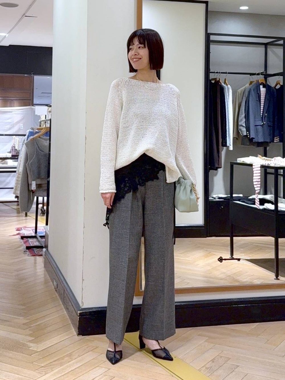 グリーン系のショルダーバッグ、ブラック系のスラックス、ブラック系のパンプスを着用したレディースの冬コーディネートの1枚目の写真