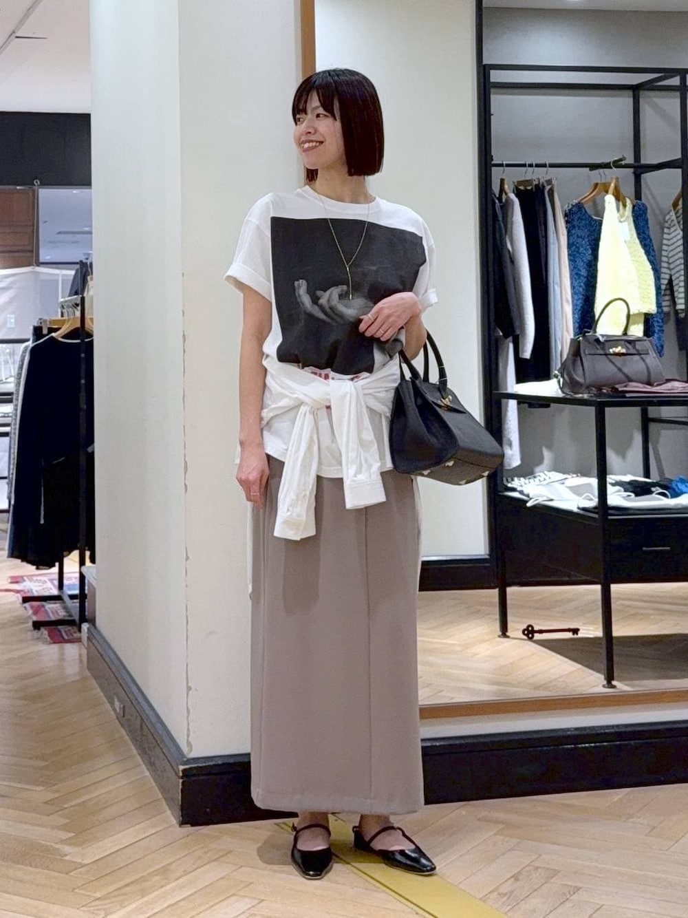 ブラック系のショルダーバッグ、ホワイト系のシャツ/ブラウス、ブラック系のパンプスを着用したレディースの春コーディネートの1枚目の写真