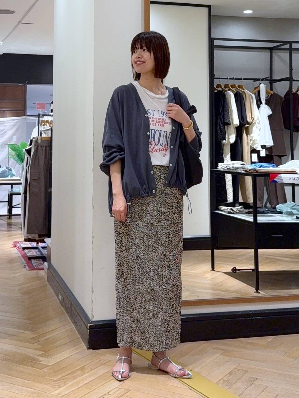 グレー系のカーディガン/ボレロ、シルバー系のサンダル、ベージュ系のスカートを着用したレディースの夏コーディネートの1枚目の写真