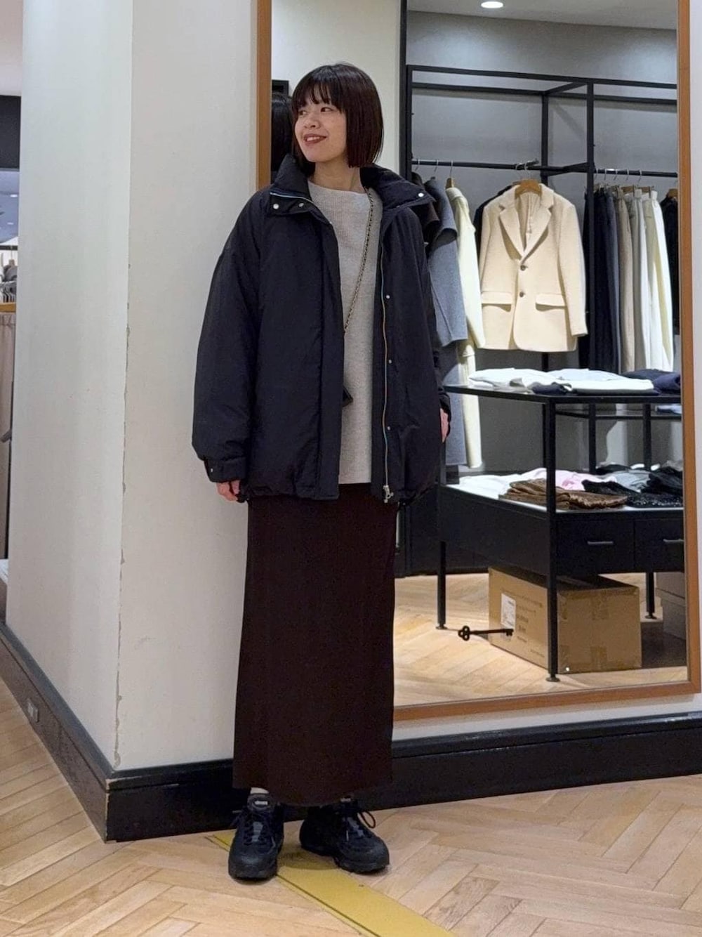 ブラック系のブルゾン、グレー系のニット/セーター、ブラウン系のスカートを着用したレディースの冬コーディネートの1枚目の写真