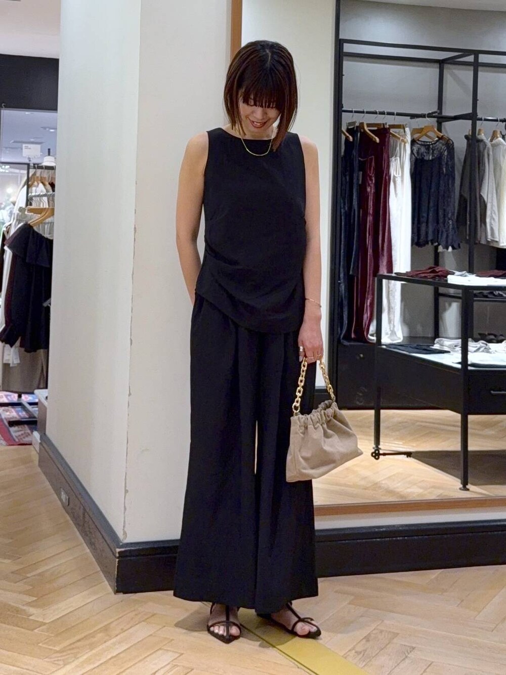 ブラウン系のサンダル、ベージュ系のショルダーバッグ、ブラック系のパンツドレスを着用したレディースの夏コーディネートの1枚目の写真