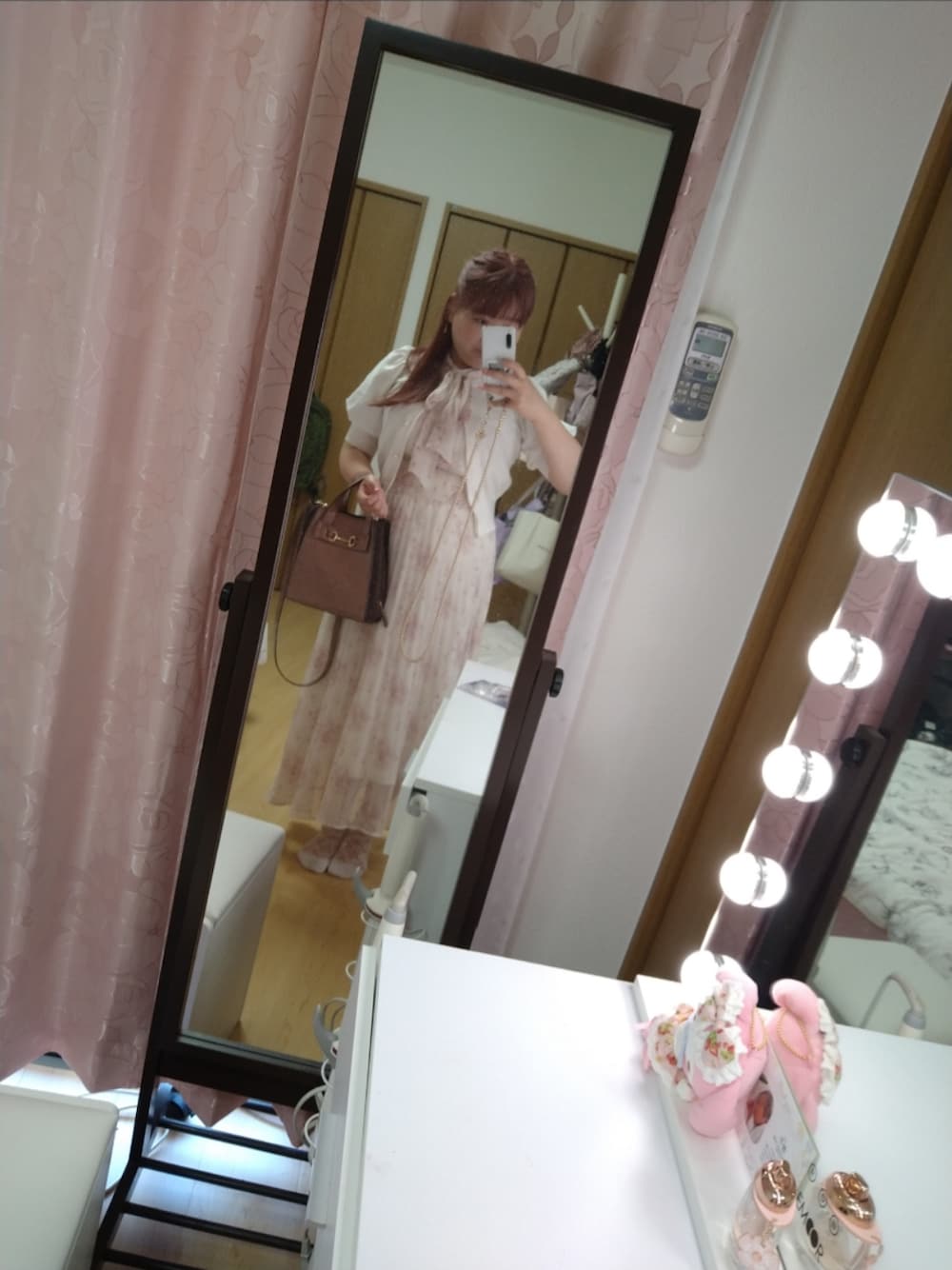 ピンク系のショルダーバッグ、ピンク系のワンピース、ホワイト系のニット/セーターを着用したレディースの春コーディネートの1枚目の写真