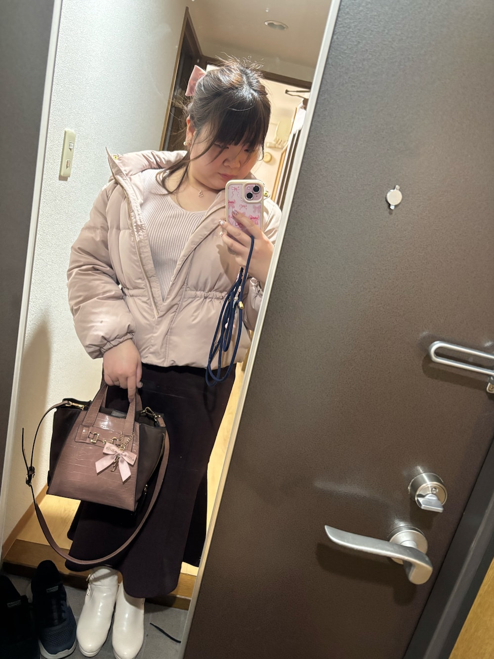 ピンク系のニット/セーター、ピンク系のダウンジャケット/コート、ピンク系のショルダーバッグを着用したレディースの冬コーディネートの1枚目の写真