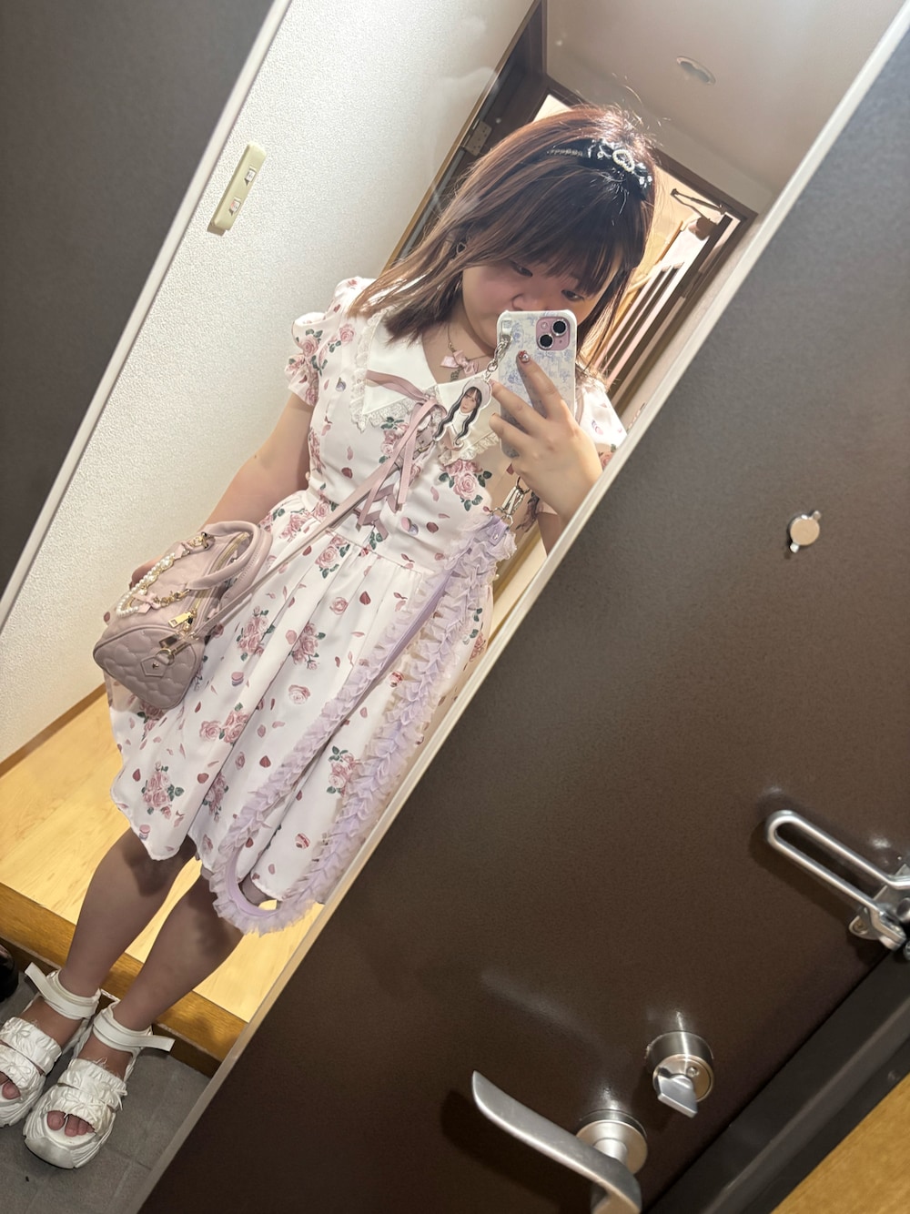 ピンク系のワンピース、ホワイト系のサンダル、ピンク系のハンドバッグを着用したレディースの秋コーディネートの1枚目の写真