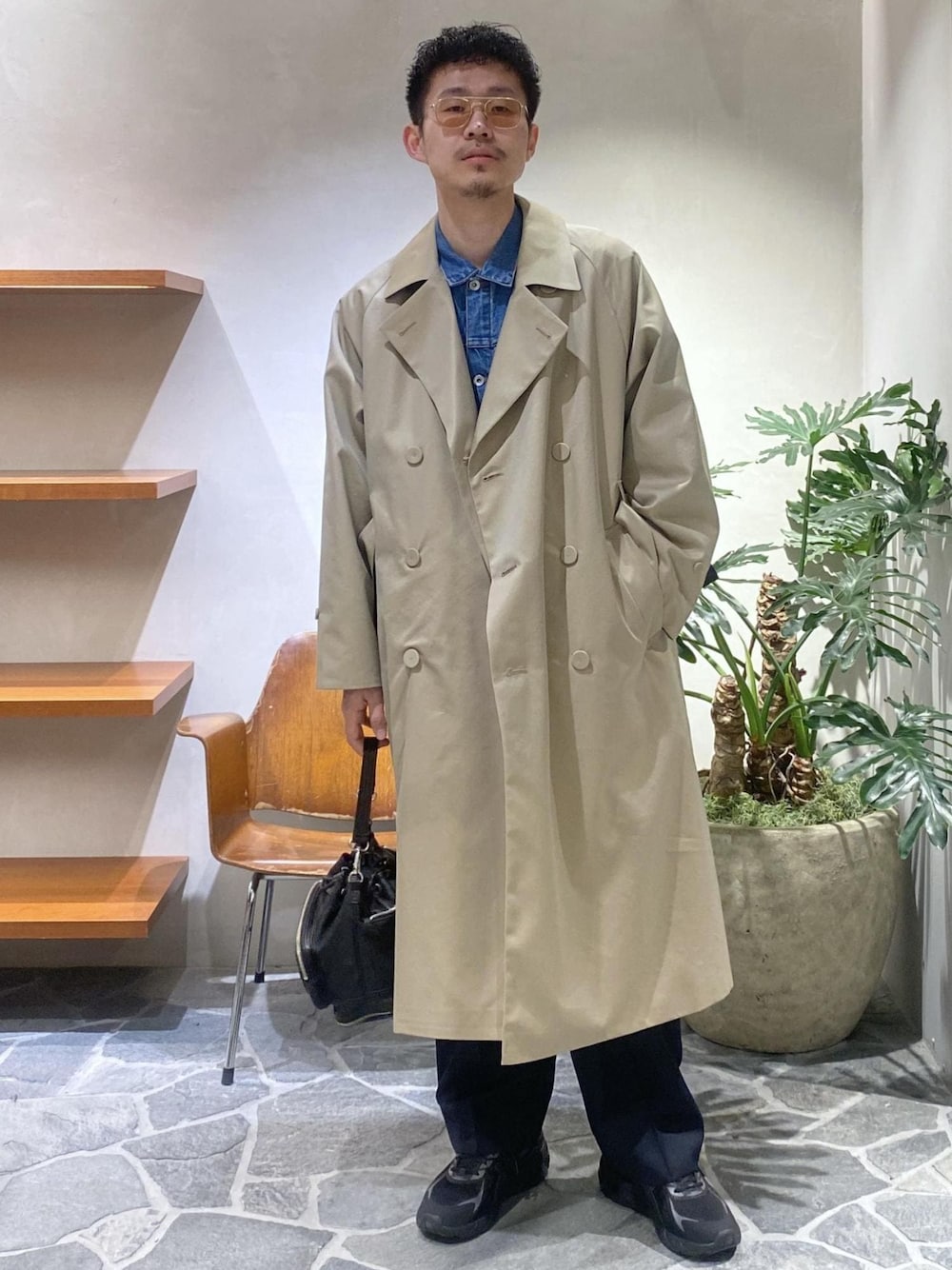 ベージュ系のトレンチコート、ブルー系のデニムジャケット、ブルー系のスラックスを着用したメンズの冬コーディネートの1枚目の写真