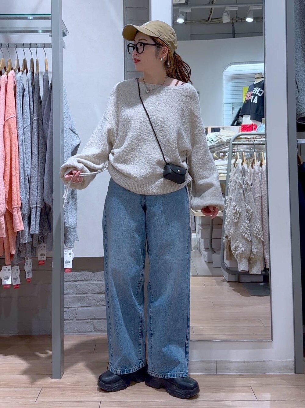 ブラック系のショルダーバッグ、ブラック系のブーツ、ブルー系のデニムパンツを着用したレディースの冬コーディネートの1枚目の写真