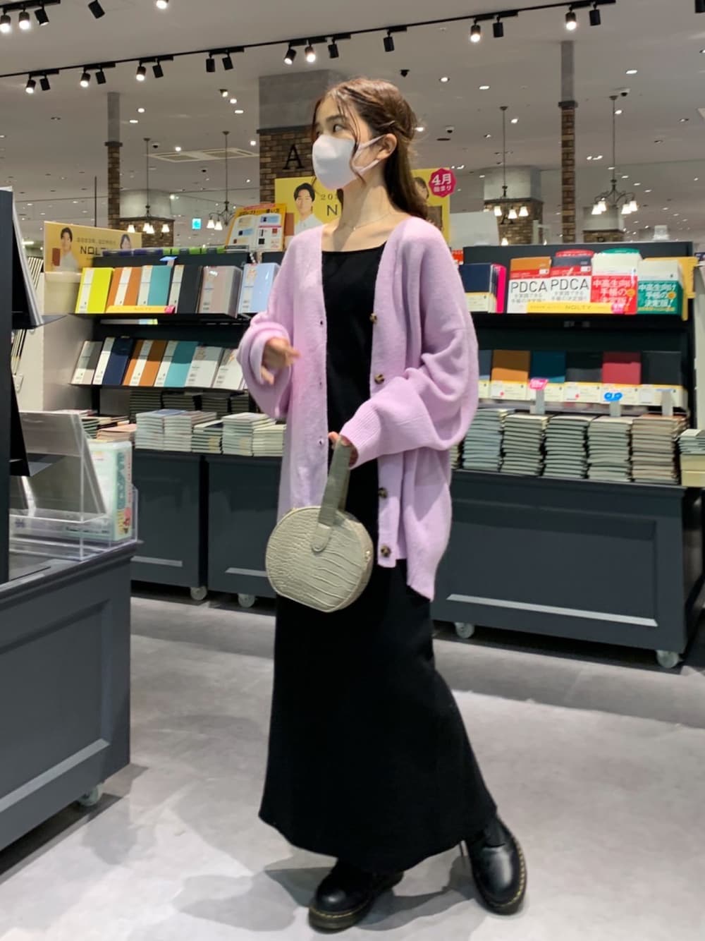 パープル系のカーディガン/ボレロ、ブラック系のワンピース、ベージュ系のショルダーバッグを着用したレディースの冬コーディネートの1枚目の写真