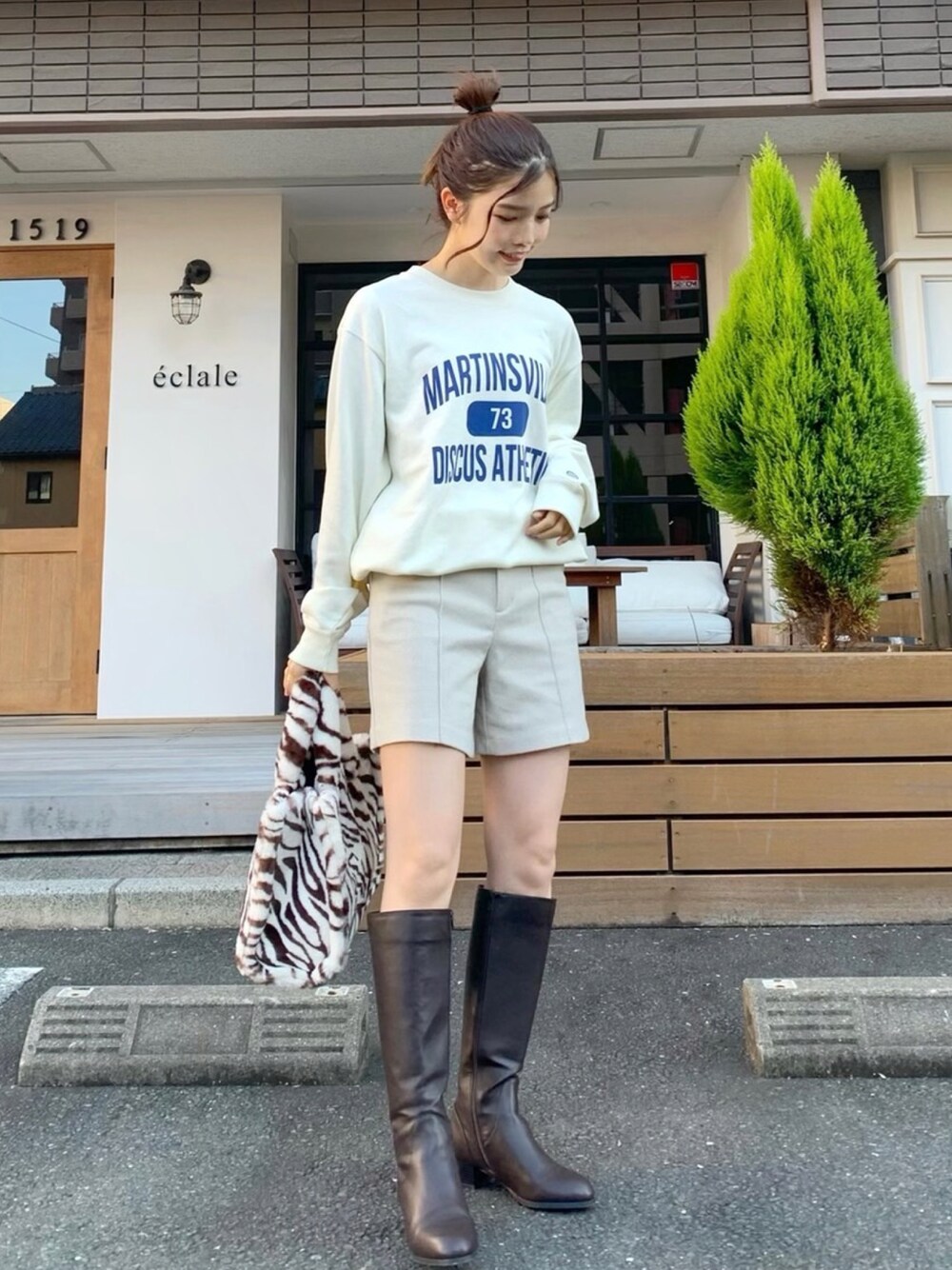 ホワイト系のスウェット、ホワイト系のパンツ、ブラウン系のバッグを着用したレディースの秋コーディネートの1枚目の写真