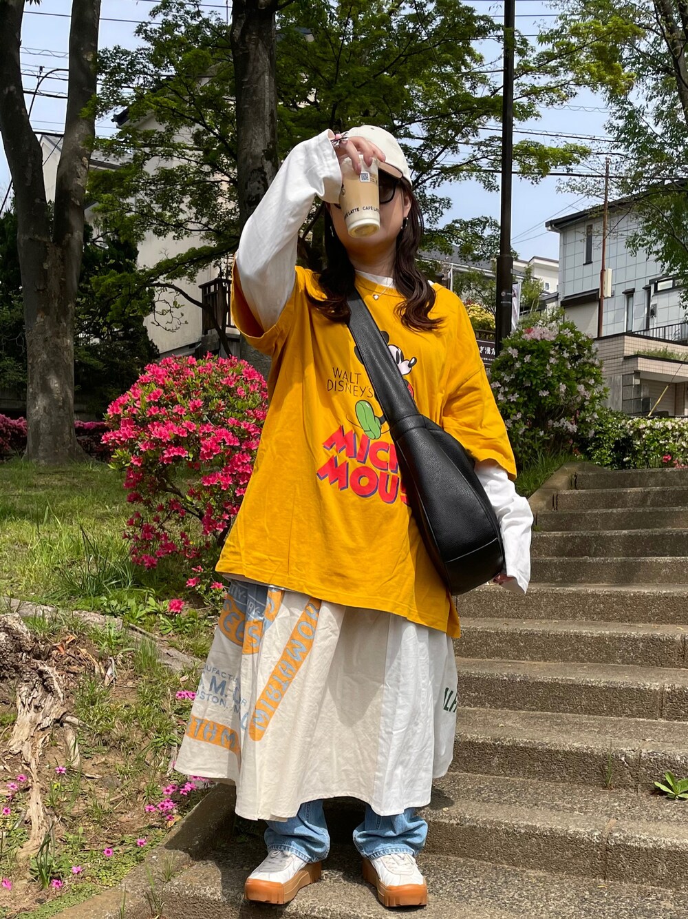 ブラック系のTシャツ/カットソー、ホワイト系のスカート、ホワイト系のスニーカーを着用したレディースの春コーディネートの1枚目の写真