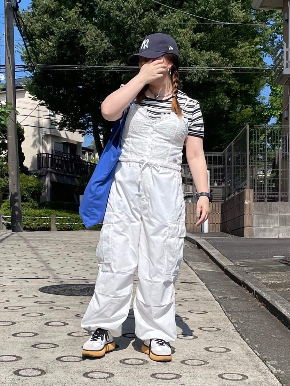 ホワイト系のキャミソール、ブルー系のトートバッグ、ホワイト系のスニーカーを着用したレディースの夏コーディネートの1枚目の写真