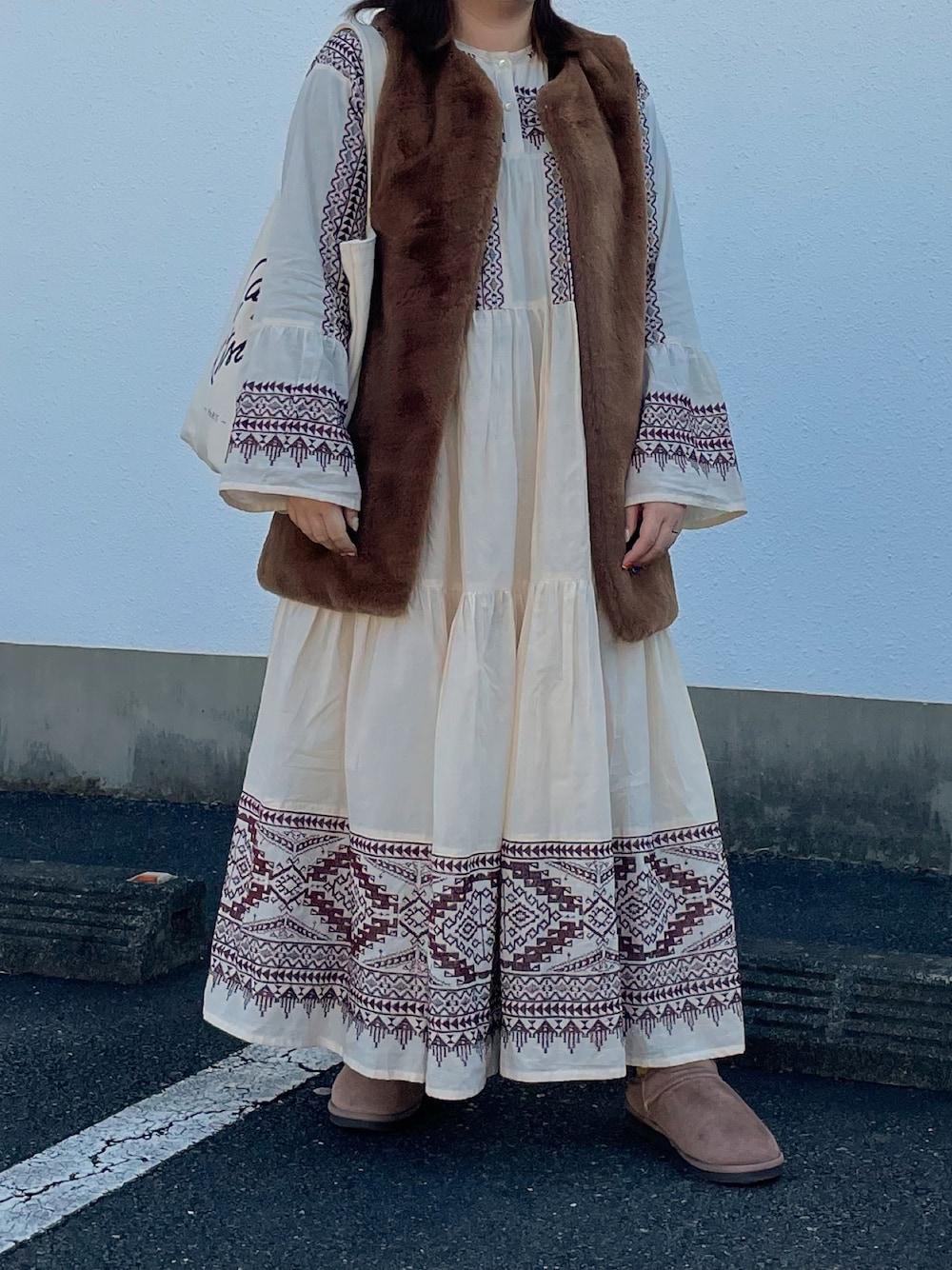 ホワイト系のワンピース、ブラウン系のベスト、ホワイト系のトートバッグを着用したレディースの秋コーディネートの1枚目の写真