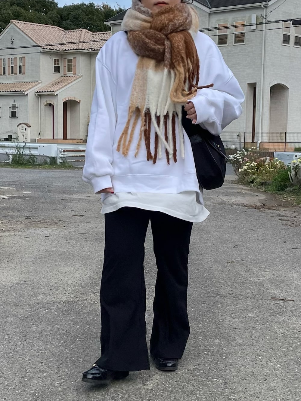 ブラック系のショルダーバッグ、ブラック系のパンツ、ホワイト系のマフラーを着用したレディースの冬コーディネートの1枚目の写真