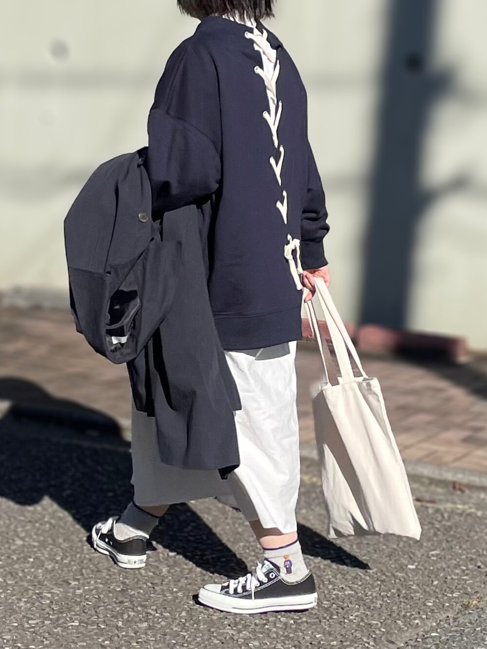 ブルー系のスウェット、ホワイト系のシャツワンピース、ブラック系のスニーカーを着用したレディースの秋コーディネートの1枚目の写真