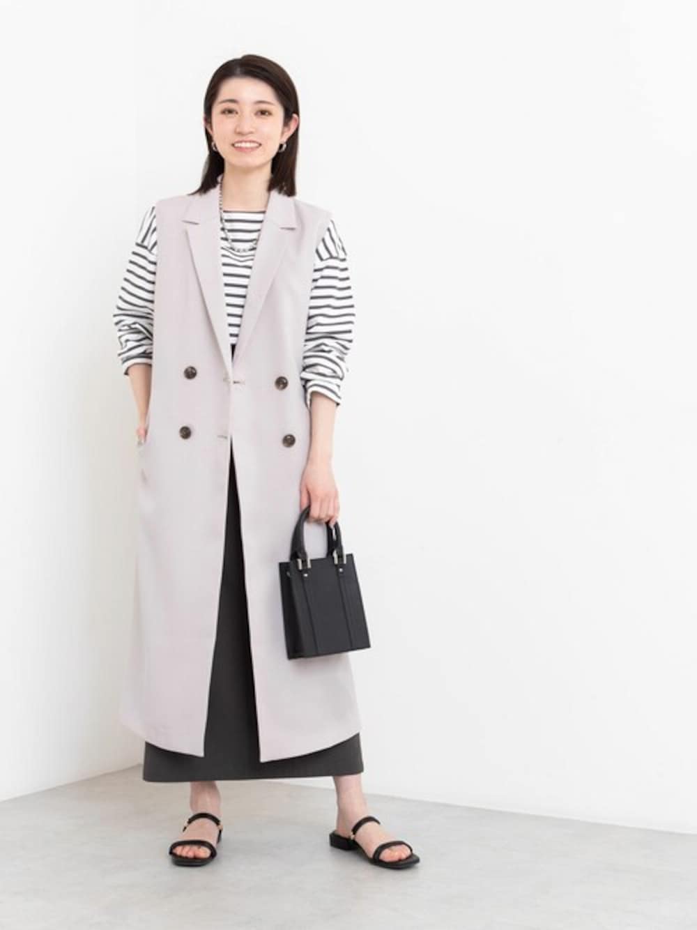 グレー系のTシャツ/カットソー、ベージュ系のベスト、グレー系のスカートを着用したレディースの春コーディネートの1枚目の写真