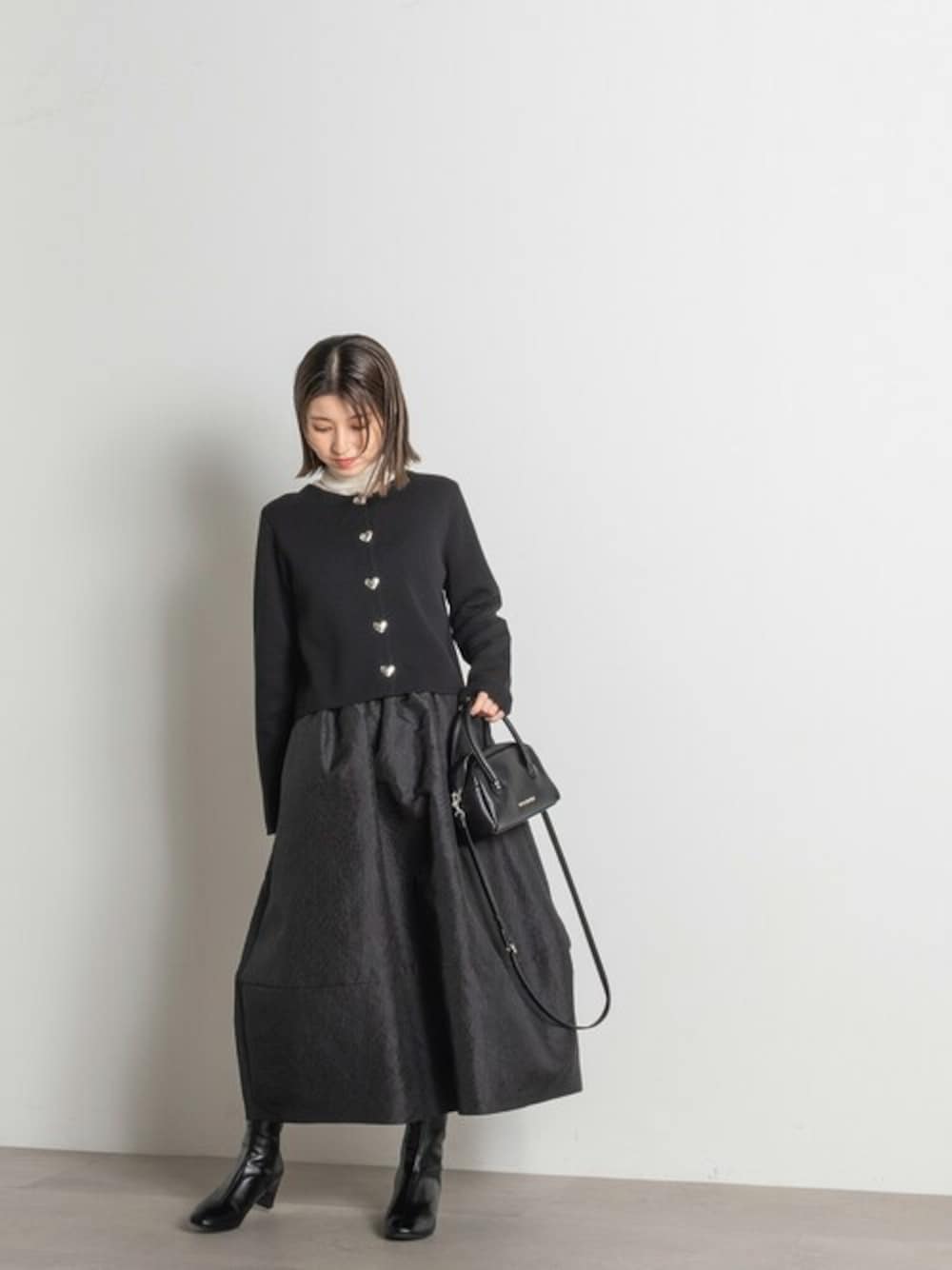 ブラック系のカーディガン/ボレロ、ホワイト系のニット/セーター、ブラック系のスカートを着用したレディースの秋コーディネートの1枚目の写真