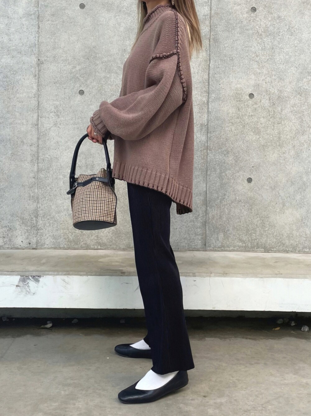 ブラウン系のニット/セーター、ホワイト系のその他パンツ、ブラック系のハンドバッグを着用したレディースの秋コーディネートの1枚目の写真