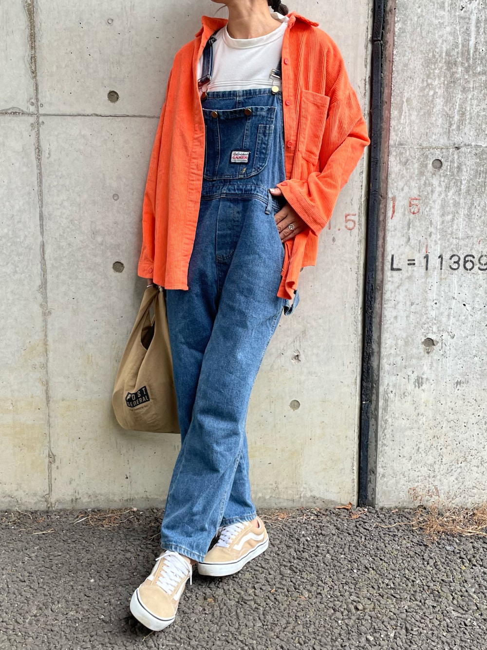オレンジ系のシャツ/ブラウス、ホワイト系のTシャツ/カットソー、ブルー系のサロペット/オーバーオールを着用したレディースの秋コーディネートの1枚目の写真