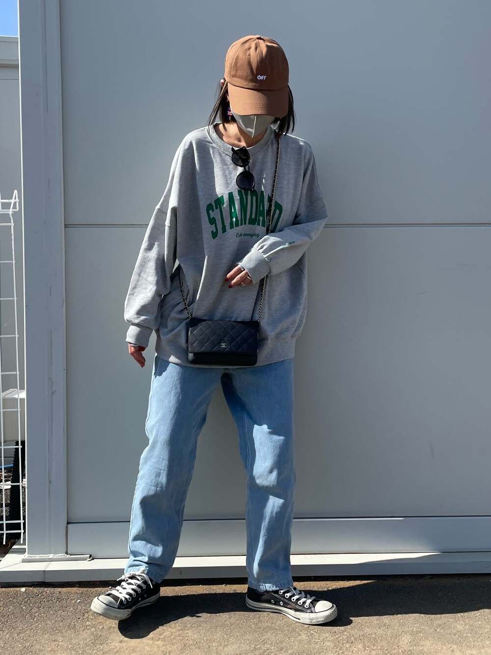 ブルー系のデニムパンツ、ブラック系のスニーカー、ブラウン系のキャップを着用したレディースの冬コーディネートの1枚目の写真