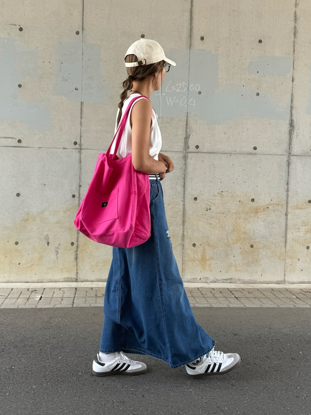 ブルー系のデニムスカート、ピンク系のトートバッグ、ホワイト系のスニーカーを着用したレディースの夏コーディネートの1枚目の写真