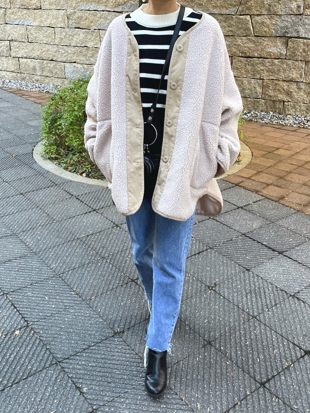 ブラック系のニット/セーター、ブルー系のデニムパンツ、ブラック系のショルダーバッグを着用したレディースの冬コーディネートの1枚目の写真