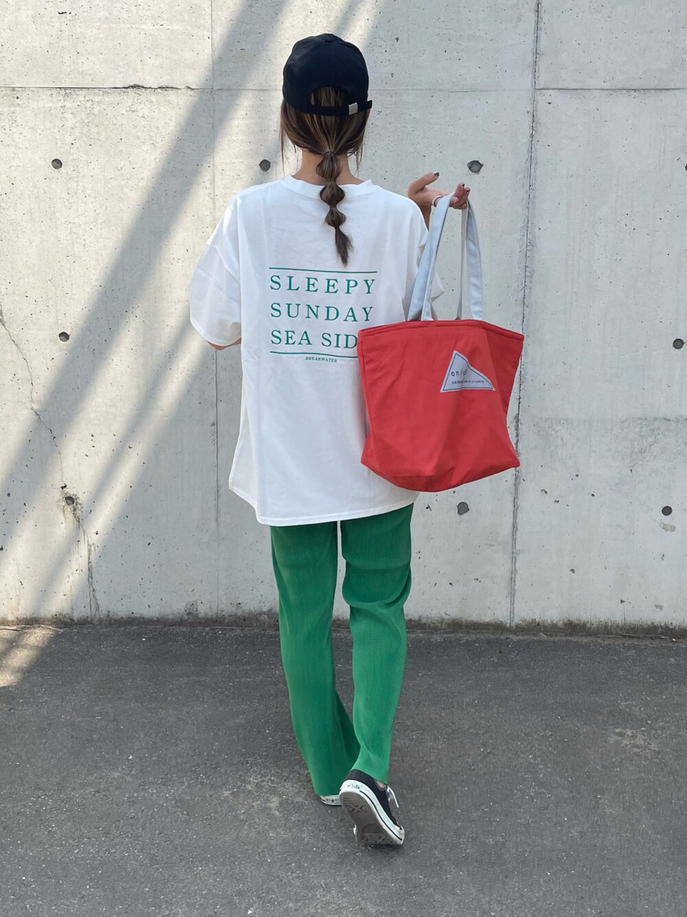 グリーン系のTシャツ/カットソー、オレンジ系のトートバッグ、ブラック系のスニーカーを着用したレディースの春コーディネートの1枚目の写真