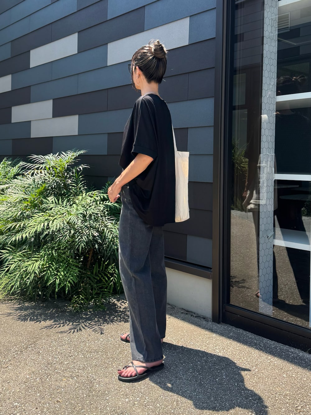 ブラック系のTシャツ/カットソー、ブラック系のデニムパンツ、ホワイト系のトートバッグを着用したレディースの夏コーディネートの1枚目の写真