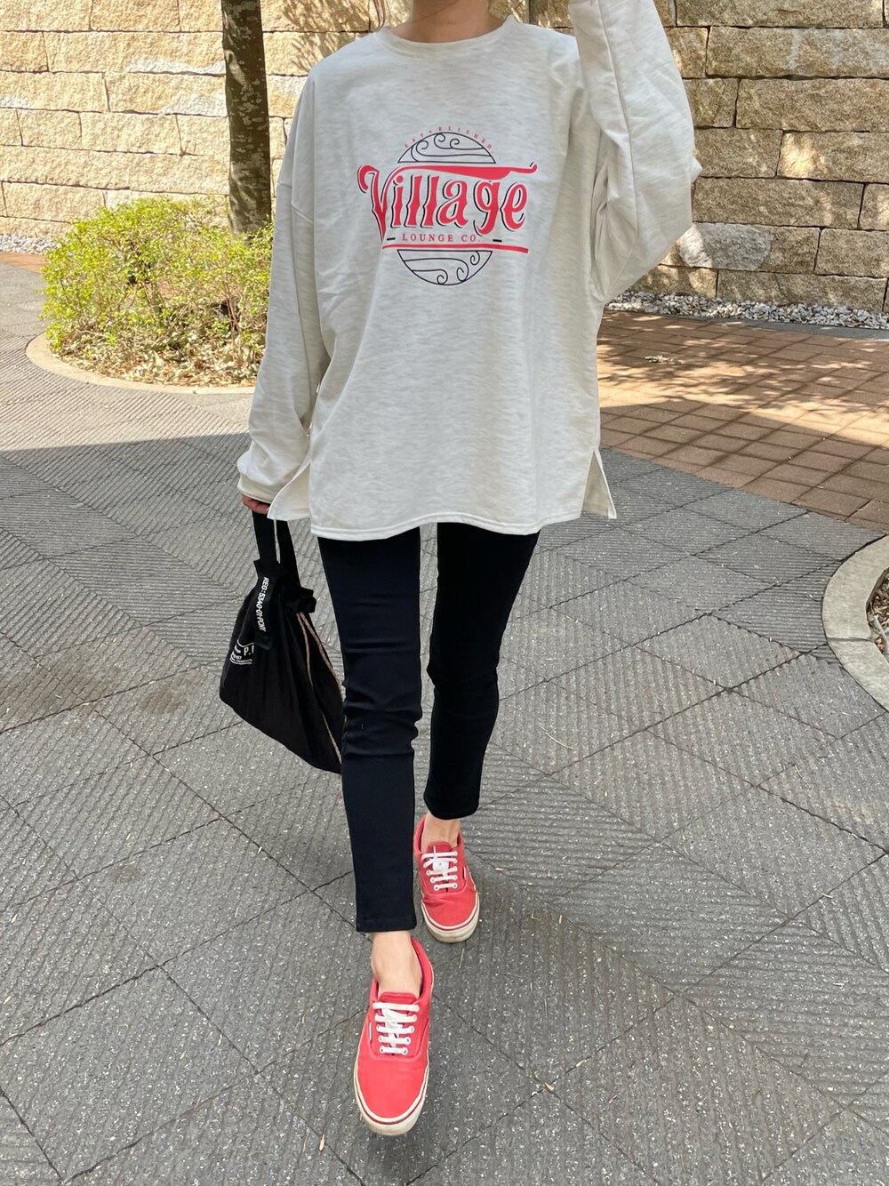 ブラック系のその他パンツ、グリーン系のエコバッグ/サブバッグ、レッド系のスニーカーを着用したレディースの春コーディネートの1枚目の写真