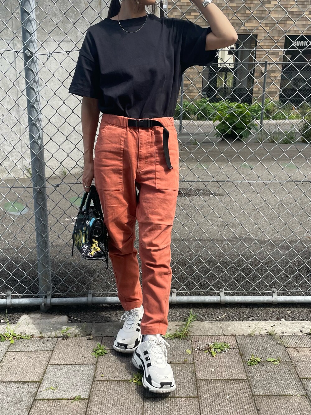 ブラック系のTシャツ/カットソー、レッド系のその他パンツ、ブラック系のバッグを着用したレディースの春コーディネートの1枚目の写真