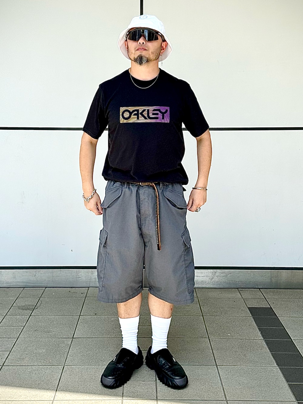 「夏コーデ、カジュアルコーデ、ストリート、モノトーン、リラックススタイル、タックイン、バケットハット、サングラス、ショートパンツ、ハーフパンツ、モノトーンコーデ、シルバーアクセサリー、Oakley、カーゴパンツ、オーバーサイズ」｜「OAKLEYのアイテム（Tシャツ/カットソー、ブラック系）」を使った、Yoshihito Hayashiさん（メンズ・170cm）の夏コーディネートの1枚目の写真