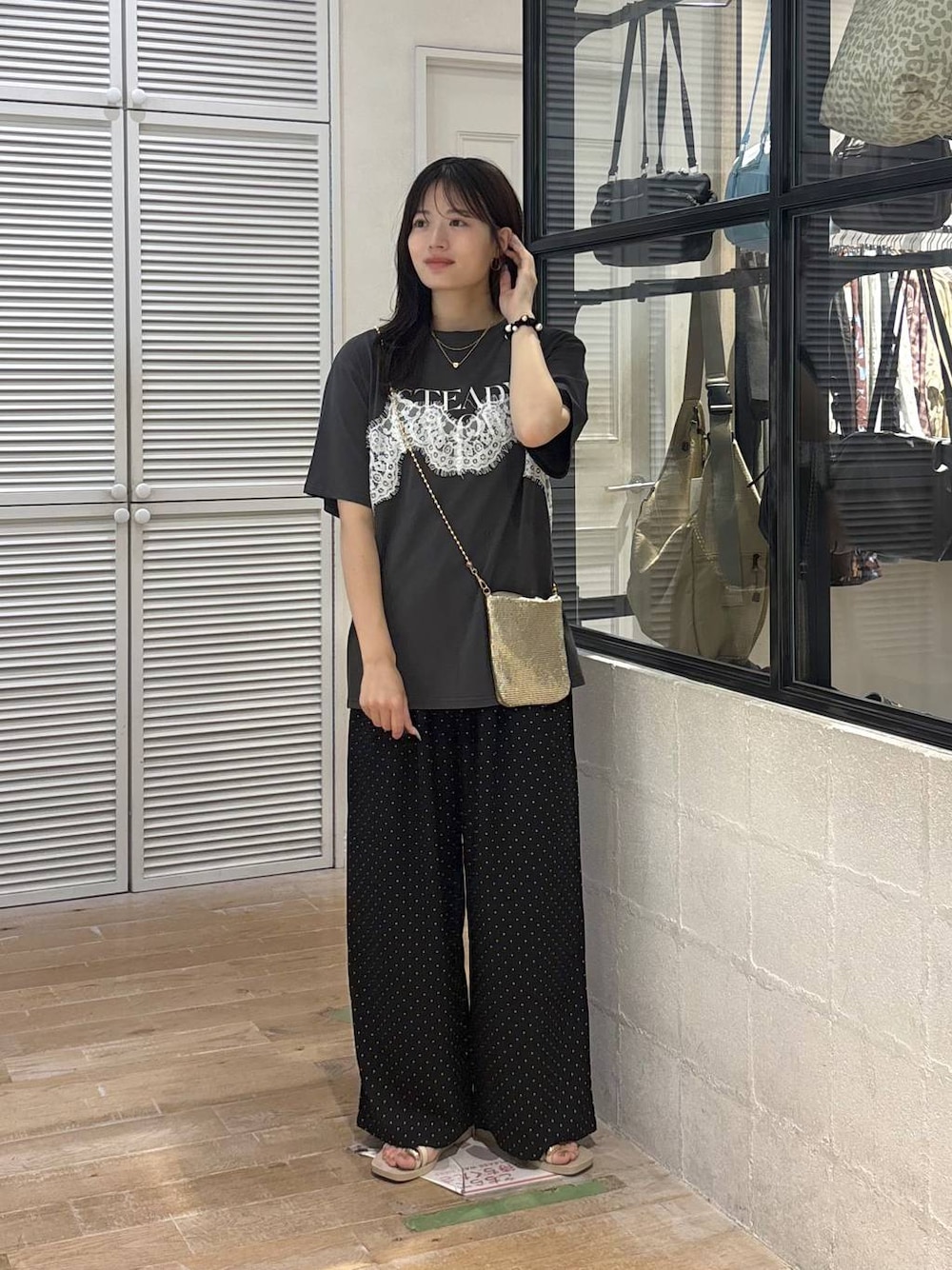 ゴールド系のショルダーバッグ、グレー系のTシャツ/カットソー、ホワイト系のサンダルを着用したレディースの夏コーディネートの1枚目の写真