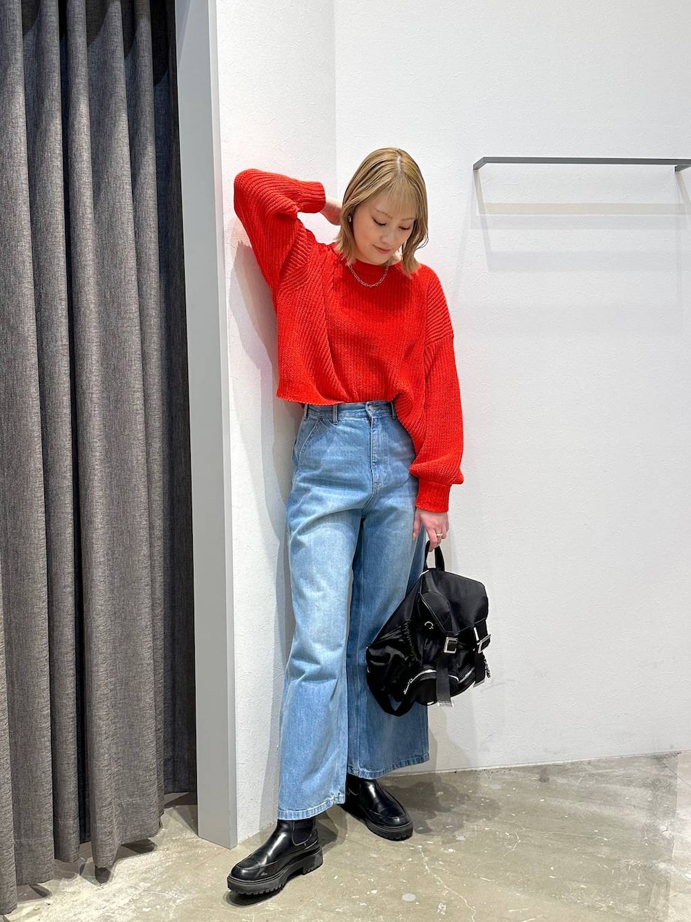 ブルー系のデニムパンツ、レッド系のニット/セーター、ブラック系のバックパック/リュックを着用したレディースの冬コーディネートの1枚目の写真