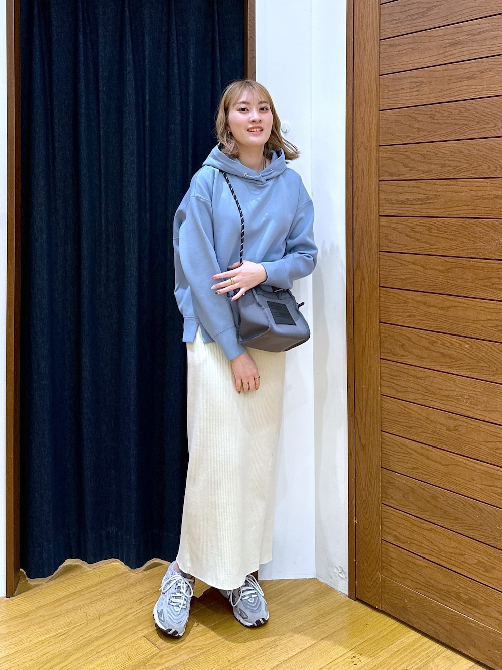 ブルー系のパーカー、グレー系のショルダーバッグ、ベージュ系のスカートを着用したレディースの春コーディネートの1枚目の写真
