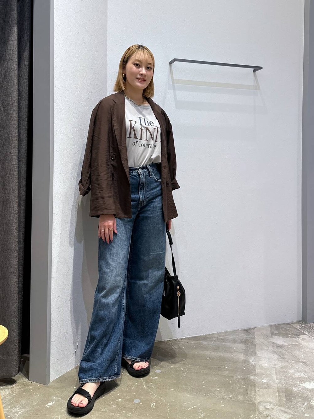 ブルー系のデニムパンツ、グレー系のTシャツ/カットソー、ブラック系のハンドバッグを着用したレディースの秋コーディネートの1枚目の写真